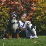 A pet sitter spending time with a dog and cat in a family home.